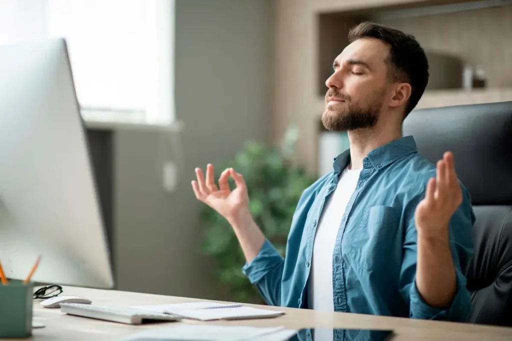 坐在電腦前深呼吸的男子